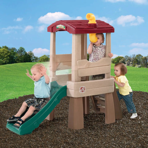 Children playing on Play Naturally Lookout Treehouse Outdoor Playset For Backyard Fun With Slide And Climber in a grassy area