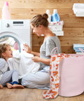 Mother and child doing laundry with Large Tall Cotton Rope Laundry Basket Hamper With Handles For Nursery And Living Room, Boho Style, Light Pink.