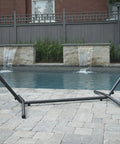 Universal Space Saving Steel Hammock Stand 9 Foot Charcoal Color, Tool Free Assembly by a pool with adjustable hooks.