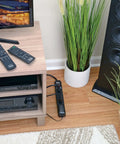 Six Outlet Surge Protector Power Strip With Six Foot Extension Cord Delivers 900 Joules Of Surge Protection, 15 Amp Circuit Breaker, UL Certified, Black on floor next to media console in living room