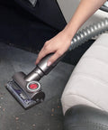 Hand using Tangle Free Turbine Upholstery Tool For DC77 And UP17 Cinetic Big Ball Animal And Allergy Uprights Genuine OEM Replacement 925067-06 to clean car upholstery