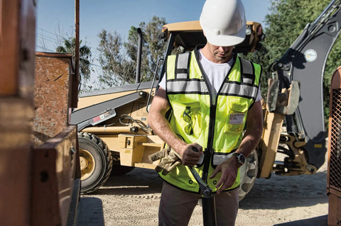 Rock Solid Hi Vis Surveyor Vest With Zipper Front Closure Ansi Class Two Type R Certified Lime Polyester Reflective Safety Vest Featuring Kickass Stripes And Hefty Tool Pockets For Xl worn by worker using tools on job site.