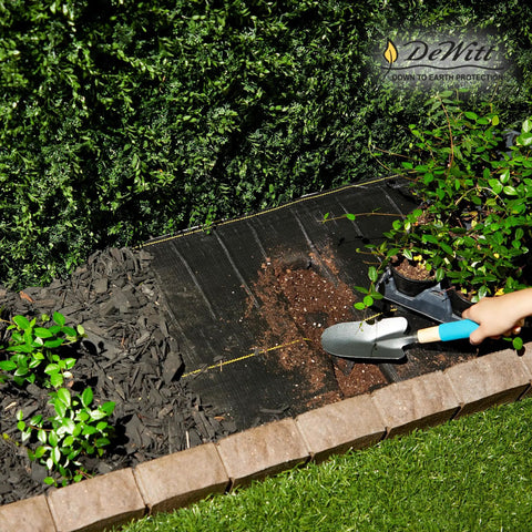 Heavy-Duty Weed Barrier Fabric 4 By 100 Feet Breathable Woven Polypropylene Ground Cover installed in a garden bed.