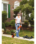 Woman using 3-In-1 Electric Lawn Mower, Trimmer And Edger With 6.5 Amp Motor, 12 Inch Cutting Width on grass in front of house