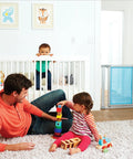 Living room with children playing and an adult, Vibe Mesh And Steel Baby Gate In Berry with Turnkey Mounts in background.