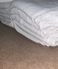 2500 Count White Shop Towels For Mechanics, Industrial Grade 14x14, 100 Percent Cotton Rags stacked and tied on a surface