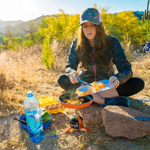 Person using Summit Skillet Nonstick Camping Cookware For Backpacking Stoves outdoors to cook with fresh ingredients.