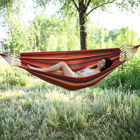 Person relaxing on Two Person Portable Camping Hammock Bed With Anti Roll Balance Beam And Tree Straps, 550 Pound Capacity, red, outdoor