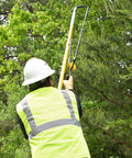 Arborist using Pro Grade Arborist Throw Line Launcher Starter Kit with dual poles for tree work under a green canopy