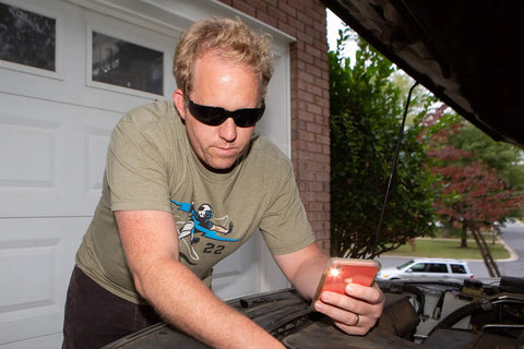 Man wearing black safety glasses working on car engine outdoors, Safety Glasses Pack Of 12 For DIY Projects Garden Work Cycling And Sports With Impact Resistant Lenses UV Protection Anti Scratch Ballistic Grade Durability Clear And Privacy Lenses ANSI Z87 1 Certified For Comfort And All Day Wear usage.