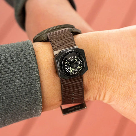Slip On Wrist Compass For Survival Gear And Outdoor Adventurers attached to a brown watch band, easy read dial
