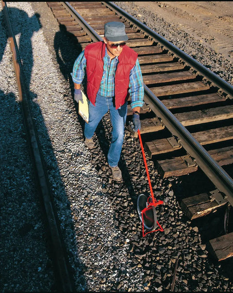 Person using Rolatape 32-415 Heavy-Duty Measuring Wheel With All Steel Construction for measuring along railway tracks.