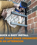 Person installing Garage Ready Six Level Wood Organizer And Lumber Storage Metal Rack on brick wall using a drill.
