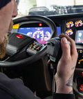 Driver using 636LSE 4-Pin Noise Canceling CB Microphone for Close-Talk Handheld Use, XLR Silver Anniversary Edition in vehicle cabin.