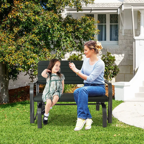 Woman and child sitting on Outdoor Glider Bench With Steel Frame 2 Seat Porch Loveseat Swing For Patio Garden And Backyard Rocking Chair For Porch And Lawn In Dark Green Smooth Quiet Glide And Cozy Outdoor Relaxation in a backyard