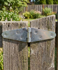 Close-up of Heavy Duty 6 Pack T Hinges with mounting screws on rustic wooden barn door for gates.