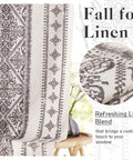 Close-up of patterned linen fabric with floral vase in background, showcasing refreshing linen blend for home décor.