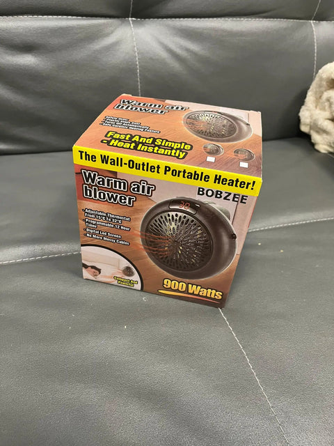 Box of a 900 watts warm air blower portable heater on a gray sofa
