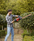 Man using Heavy Duty Electric Hedge Trimmer With 420 Watt Motor And 45CM Cutting Blade for yard maintenance.