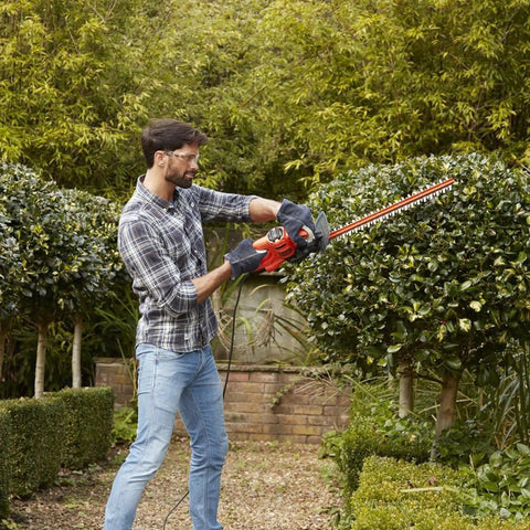 Man using Heavy Duty Electric Hedge Trimmer With 420 Watt Motor And 45CM Cutting Blade for yard maintenance.