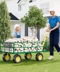 Woman pulling a green cart with logs and child seated, outdoors