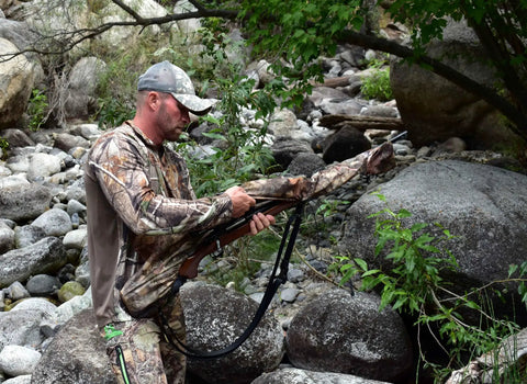 Hunter using Heavy Duty Weatherproof Long Rifle And Shotgun Slicker All Weather Rain Guard Alpine Mountain Camo Fits 38 To 56 Inch Barrels For Rifles Or Shotguns 2 Pack D24 in rocky forest