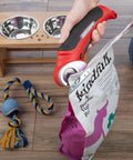 Stalwart Cordless Electric Scissors In Vibrant Red cutting through a dog food bag, showcasing automatic sharpening feature.