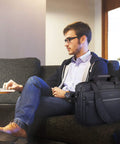 Expandable Water Repellent Laptop Briefcase For 17.3 Inch Laptop With RFID Pockets next to man using laptop on sofa