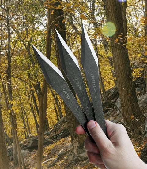 Hand holding three Six Pack 9.4 Inch No Spin Throwing Spikes Set in Durable 420HC Stainless Steel for outdoor use.