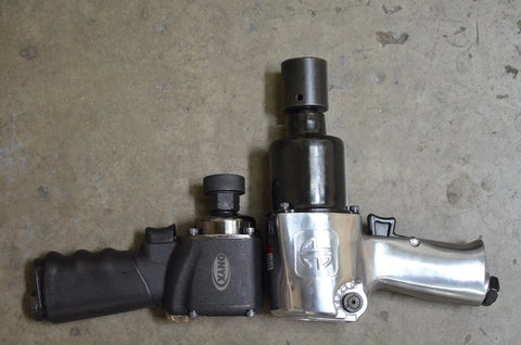 Two impact wrenches on concrete floor, showcasing size comparison with 15-Piece 1/2 Inch Drive Low Profile Nano Impact Socket Set Metric Stubby Design.