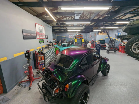 Fresh Shop Grade Superflake Colorshift Basecoat Paint Gallon Ready To Spray With Slow Reducer Binder For Custom Rigs Delivering Dope Shiftin Shades on a custom purple vehicle in a garage workshop.