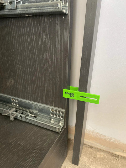 3 Piece Adjustable Carpenter Jig Set Helps You Nail Scribing Fillers And Toe Kicks Dead On With No Sweat Setup on a cabinet side.