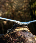 Full On Mountain Bike Handlebar, 31.8mm Clamp, 785mm Wide, 30mm Rise Beefy Alloy Riser Bar on rustic log, outdoor background