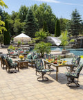 Outdoor patio set with chairs and table by a pool, surrounded by greenery and decorated with tropical-themed cushions.