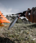 Person using 14-In-1 Multitool With Needlenose Pliers, Serrated Knife, Wire Crimper to secure tent outdoors