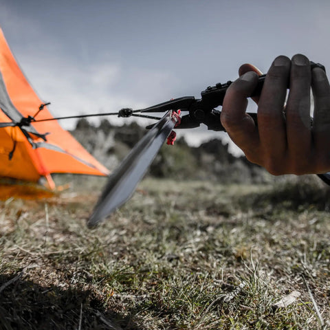 Person using 14-In-1 Multitool With Needlenose Pliers, Serrated Knife, Wire Crimper to secure tent outdoors