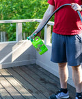 Person using EZ Deck Fence And Patio Wash 64 Oz Mold And Mildew Killer with hose end sprayer on wooden deck.