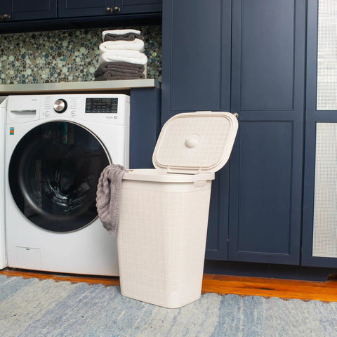 Slim Laundry Hamper With Lid 50L Capacity Clothes Basket in ivory plastic with a wicker look in a laundry room with washing machine.