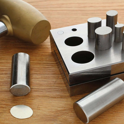 Oval Disc Cutter Set With Seven Punches And Die For Soft Metal Up To 14 Gauge shown with steel punches and wooden base.
