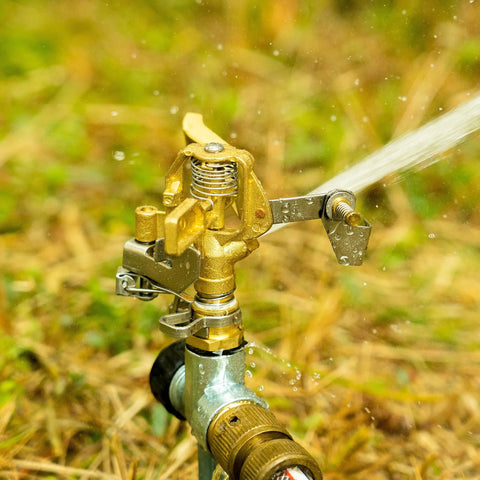 Heavy Duty Brass Impact Sprinklers Deliver Sick Durability, Adjustable Zero To Three Sixty Rotation For Huge Yard And Patio Watering, Rock Solid Build With Premium Nozzles, Fits Half Inch Pipe, Makes Your Landscape Look Fly, Reliable Four Piece Set. Close-up of sprinkler head spraying water.