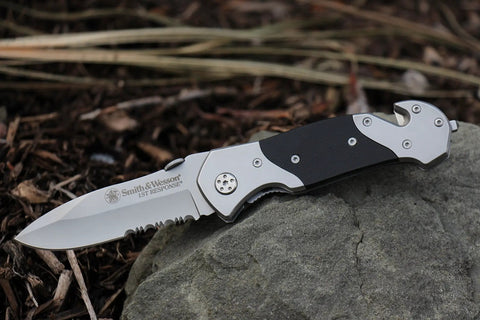 Knockout 8 Inch Folding Knife Packing A 3.3 Inch Drop Point Serrated High Carbon Stainless Blade And G10 Grip Handle on a stone.