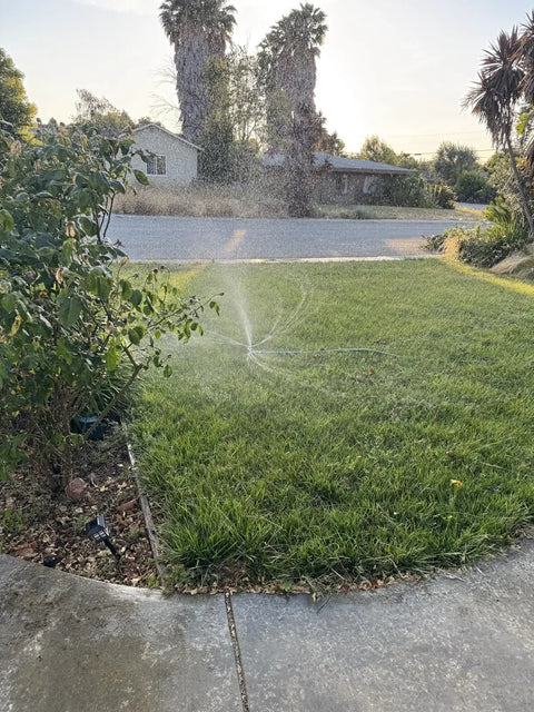 Heavy Duty Metal 3-Arm Rotating Sprinkler With Wheeled Base in action watering small yard with 360 degree coverage