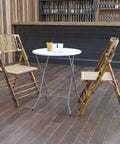 Two Foot Round Folding Event Table White Plastic Banquet Table For Indoor Outdoor Use set up with bamboo chairs on wooden deck