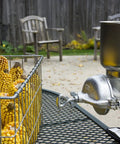GM 150 Grain Mill With Tin Coated Cast Iron Large Hopper on table with corn; adjustable clamp visible