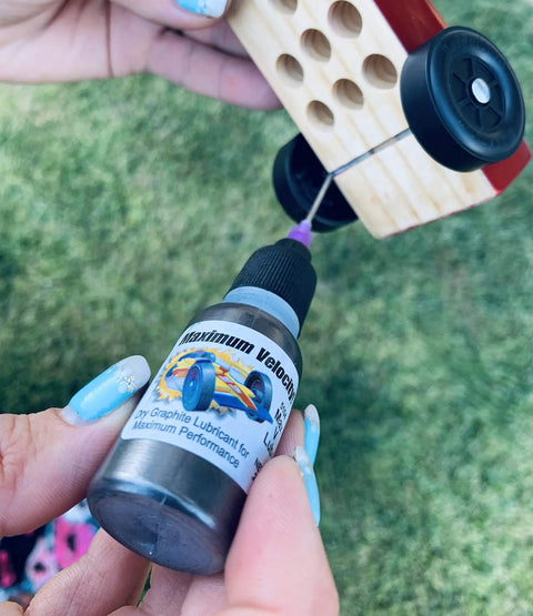 Applying Premium Pinewood Derby Graphite Powder with Easy Application Tip to Car Wheels for Top Speeds