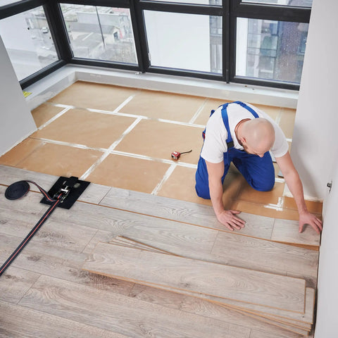 Installer using Flooring Strap Clamps Set 2 Pack 16 Foot Ratchet Tie Down Straps for DIY Flooring Installation in a room.