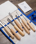 Pro Level Wood Carving Chisel Set Seven Piece Gouges With Cr-V 60 Steel Freakin Sharp Blades displayed on a canvas roll with ash handles.
