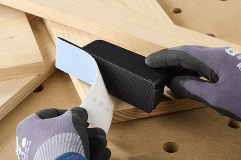 Hands applying StickFix abrasive sheet to Pocket StickFix Hand Sanding Block With Quick Change Hook And Loop System on wood surface