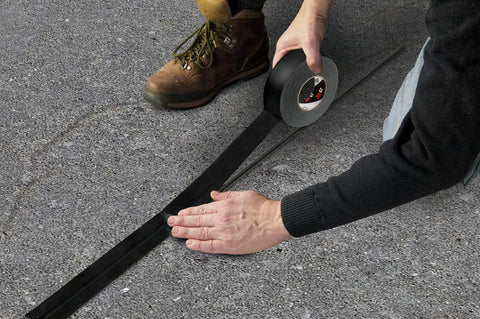 Person applying Pro Grade Matte Cloth Gaffers Tape GT3 72mm Wide By 50m Long 11 Mil Thick Hand Tearable on outdoor surface