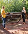 Two women setting up a Six Foot Folding Picnic Table With Classic Rugged Steel Frame Seats Eight UV Protected Top Weather and Rust Resistant Flat Fold on a deck.